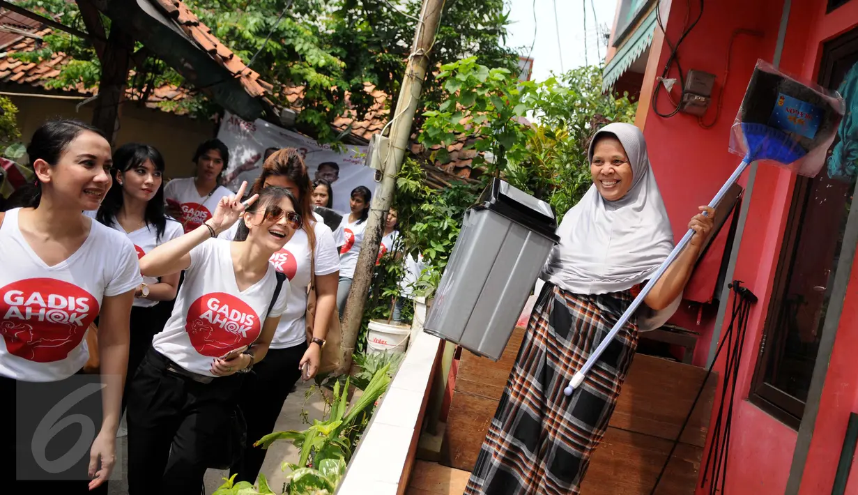 Relawan dari Gerakan Aksi Srikandi Coblos Ahok (Gadis Ahok) memberikan sapu dan tempat sampah ke warga di kawasan Cipete, Jakarta Selatan, Senin (26/12). Sebanyak 150an kantong sampah dan sapu dibagikan ke warga. (Liputan6.com/Gempur M Surya)