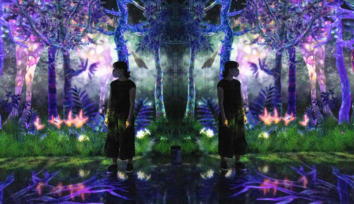 Seorang anggota staf berdiri di instalasi digital interaktif bernama "Catching and Collecting Forest" selama pratinjau media "teamLab Forest" di gedung hiburan BOSS E・ZO FUKUOKA di Fukuoka, Jepang, Jumat (16/7/2021). (YUKI IWAMURA/AFP)