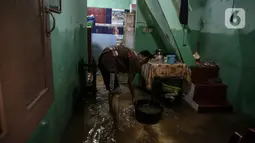 Warga bersih-bersih rumah usai terendam banjir di kawasan Kampung Melayu, Jakarta, Senin (8/11/2021). Banjir akibat luapan Kali Ciliwung tersebut merendam pemukiman setinggi 60 cm sejak 7 November 2021 sore. (Liputan6.com/Faizal Fanani)