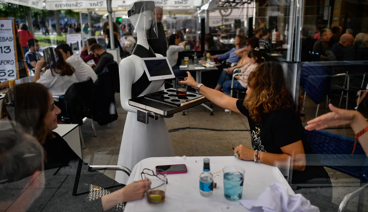 Sebuah robot yang dikenal sebagai "Alexia" menyajikan minuman kepada pengunjung sebuah bar di alun-alun Plaza del Castillo, di Pamplona, Spanyol pada 5 Juni 2020. Robot tersebut digunakan untuk mengurangi penyebaran virus corona Covid-19. (AP Photo/Alvaro Barrientos)