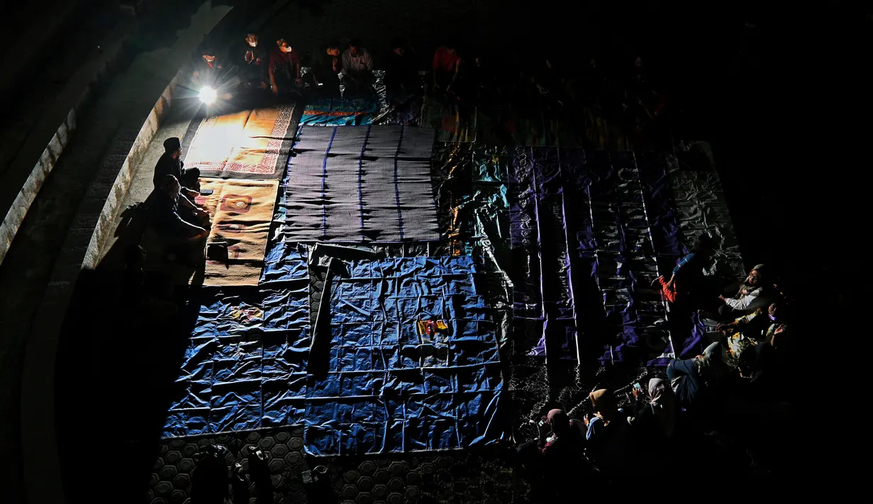 Sejumlah warga menghadiri upacara doa pada malam peringatan 17 tahun tsunami Boxing Day 2004 di monumen Kapal Tsunami Lampulo di Banda Aceh (25/12/2021). (AFP/Chaideer Mahyuddin)