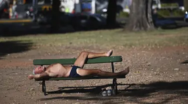 Seorang pria berjemur saat gelombang panas musim panas di bangku taman di Bosques de Palermo, Buenos Aires, Argentina (14/1/2022). Fenomena gelombang panas di Argentina sudah diperkirakan mencapai puncaknya pada minggu ini dengan temperatur mencapai 40 derajat celcius. (AP Photo/Mario De Fina)