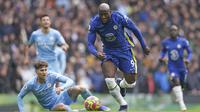 Penyerang Chelsea, Romelu Lukaku (tengah) membawa bola melewati bek Manchester City, John Stones saat pertandingan Liga Inggris di stadion Etihad, Sabtu (15/1/2022). Hasil ini membuat Man City unggul 13 poin atas Chelsea yang menempati peringkat dua di klasemen. (AP Photo/Dave Thompson)