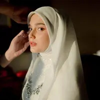 Sentuhan mahkota minimalis yang bertengger di atas hijab menambah kesan royal dan berkelas, seakan menegaskan bahwa ia adalah ratu di hari istimewanya. Riasan wajahnya pun tampil flawless, dengan nuansa soft glam yang menonjolkan kecantikannya secara alami tanpa terkesan berlebihan. [@yxsmine.ow].