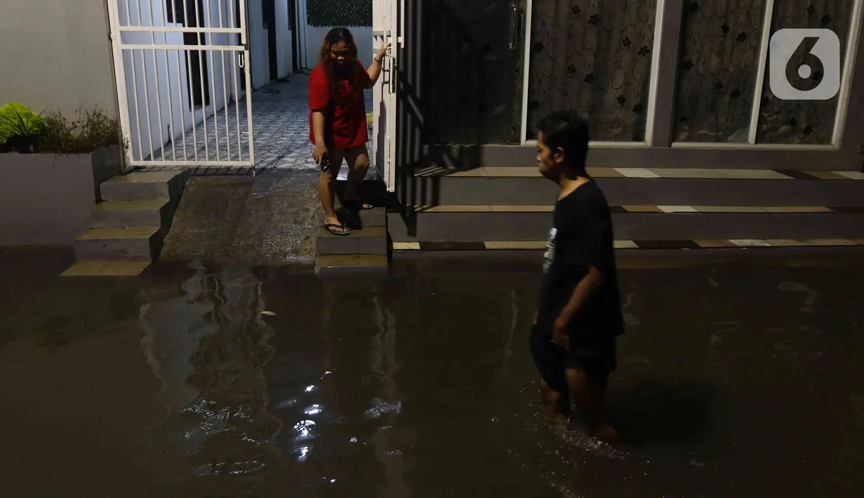 Warga sedang berjalan di tengah banjir yang melanda Jalan Bangka, Jakarta, Rabu (4/1/2023). Hujan deras yang terjadi pada Rabu sore membuat Kali Mampang meluap hingga menyebabkan banjir di kawasan tersebut dengan ketinggian bervariasi mulai dari 40 hingga 60 cm. (Liputan6.com/Herman Zakharia)