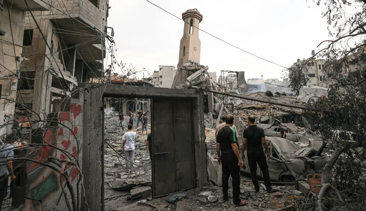 Orang-orang berdiri di antara puing-puing masjid yang hancur selama serangan udara Israel, di Kota Gaza pada 9 Oktober 2023. (Mahmud HAMS/AFP)