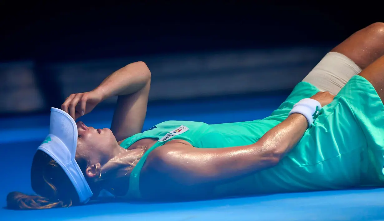 Petenis Prancis, Alize Cornet tergeletak di lapangan akibat cuaca yang begitu panas saat bertanding melawan petenis Belgia Elise Mertens di kejuaraan tenis Australia Terbuka di Melbourne, Australia, (19/1). (AP Photo / Andy Brownbill)
