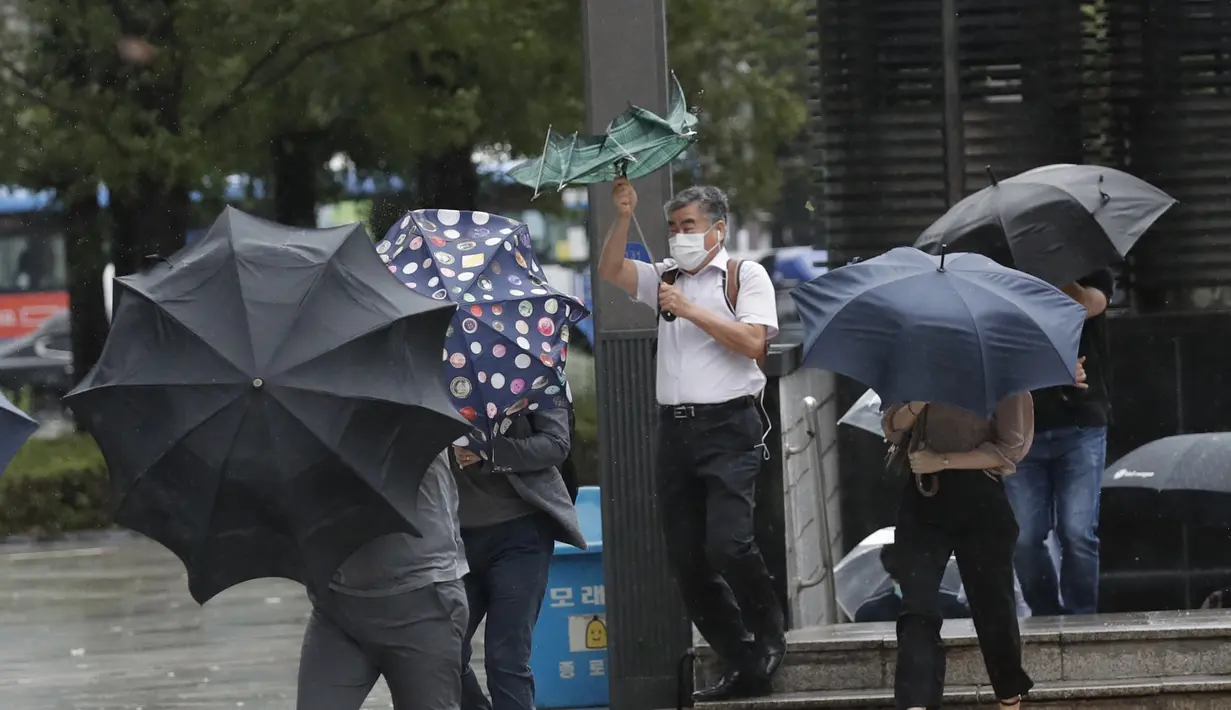 Orang-orang berjuang dengan payung mereka melawan angin kencang dan hujan di pusat kota Seoul, Korea Selatan, Kamisn (3/9/2020). Topan Maysak kuat melanda wilayah semenanjung Korea. (AP Photo/Lee Jin-man)