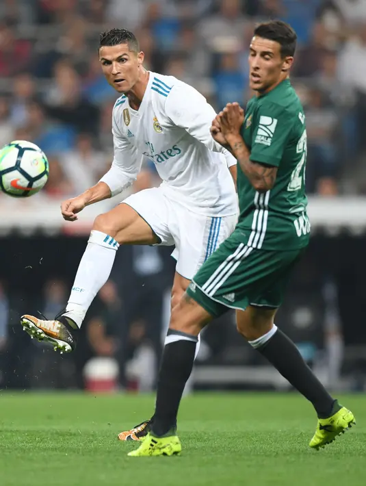 Penyerang Real Madrid, Cristiano Ronaldo berebut bola dengan pemain Real Betis dalam laga pekan lima La Liga di Santiago Bernabeu, Rabu (20/9). Real Madrid keok 0-1 dari tamunya, Real Betis. (GABRIEL BOUYS/AFP)