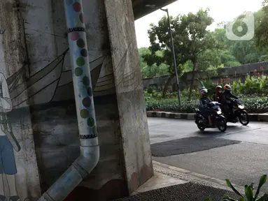 Pengendara motor melintasi sisi tiang penyangga Jalan Tol Pelabuhan Lingkar Dalam Jakarta di Jalan Ancol Timur, Jakarta, Selasa (16/6/2020). Seni mural yang dulu menghiasi tiang-tiang jalan tol di kawasan tersebut kini terlihat kusam dan berdebu. (Liputan6.com/Helmi Fithriansyah)