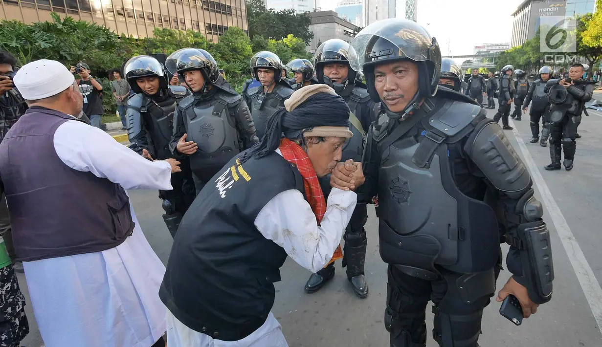 Peserta aksi mencium tangan Polisi dari kesatuan Brimob saat gelar doa bersama di depan kantor Bawaslu, Jakarta, Jumat (24/5/2019). Mereka datang untuk mendoakan para demonstran yang meninggal saat aksi 21-22 Mei, pasca hasil penghitungan suara Pemilu 2019. (Liputan6.com/Herman Zakharia)