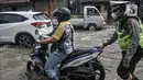 Petugas kepolisian mendorong sepeda motor warga yang mogok akibat menerobos banjir rob di Jalan Lodan Raya, Ancol, Jakarta, Senin (6/12/2021). BMKG mengimbau warga agar tetap waspada dengan kemungkinan terjadinya banjir rob selama sepekan ke depan. (merdeka.com/Iqbal S Nugroho)