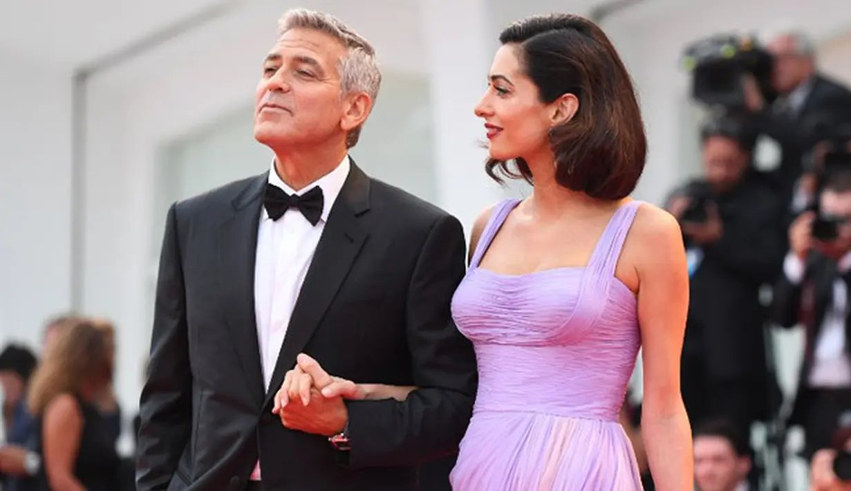 Beberapa bulan lalu Amal dan George baru saja dikaruniai sepasang anak kembar, dan keduanya pun jarang terlihat di depan umum. Namun beberapa hari lalu keduanya kembali berjalan di karpet merah bersama. (AFP/Tiziana Fabi)