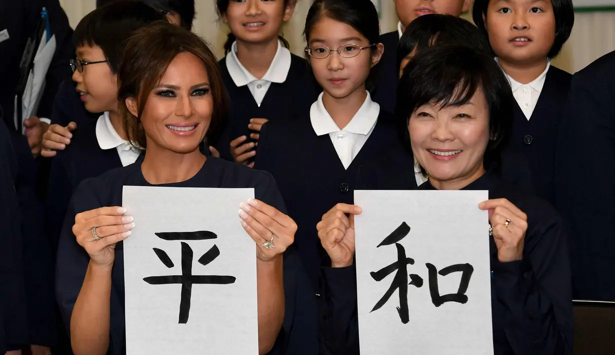 Melania Trump (kiri) dan Istri PM Jepang, Akie Abe menunjukkan huruf kanji yang berarti "Damai" saat menghadiri kelas kaligrafi di sekolah dasar Kyobashi Tsukiji, Tokyo (6/11). (AFP Photo/Pool/Toshifumi Kitamura)