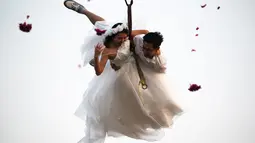 Sepasang pengantin bergelantungan pada sebuah tali saat upacara pernikahan di provinsi Ratchaburi, Thailand, Sabtu (13/2). Upacara pernikahan tersebut diikuti oleh empat pasang pengantin untuk menyambut Hari Valentine. (REUTERS/ Athit Perawongmetha)