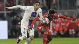 Pemain Paris Saint-Germain, Achraf Hakimi (kiri) berebut bola dengan pemain Bayern Munchen, Alphonso Davies pada laga 16 besar Liga Champions 2022/2023 di Allianz Arena, Munchen, Jerman, Kamis (09/03/2023) WIB. Hakimi gagal tampil baik dalam kekalahan 0-2 PSG. Ia tercatat kehilangannya 20 kali selama permainan, kalah enam dari 11 duel di lapangan, salah menempatkan enam percobaan umpan silang, dan dilewati sebanyak tiga kali. (AP Photo/Andreas Schaad)