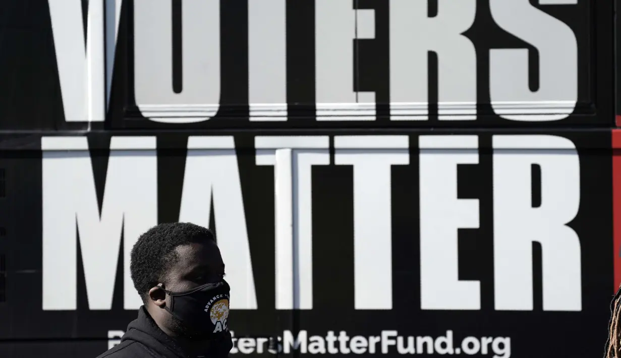 Seorang pria mengenakan masker saat berkumpul dengan sebuah kelompok untuk mendukung Black Voters Matter di tempat pemungutan suara Graham Civic Center, Graham, North Carolina, Amerika Serikat, Selasa (3/11/2020). (AP Photo/Gerry Broome)