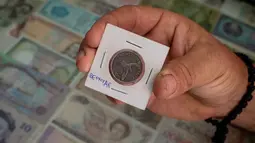 Pria Serbia, Zoran Milosevic memegang koin dari Bermuda yang menjadi tambahan koleksinya di desa Pavlovci, Belgrade, 10 September 2018. Milosevic mengumpulkan 194 mata uang berbeda dari seluruh dunia, termasuk yang tak lagi beredar. (AFP/ANDREJ ISAKOVIC)