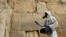 Seorang pekerja membersihkan Tembok Ratapan, situs paling suci di mana orang Yahudi dapat berdoa sebagai bagian dari langkah-langkah untuk mencegah penyebaran Covid-19 di Kota Tua Yerusalem (31/3/2020). (AFP/Emmanuel Dunand)