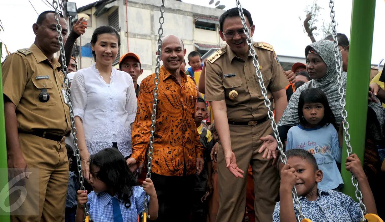 Gubernur DKI Jakarta Basuki T Purnama didampingi istri, Veronica Tan (kedua kiri) meninjau anak-anak yang tengah bermain ayunan usai meresmikan Ruang Publik Terpadu Ramah Anak (RPTRA) Karet Tengsin, Jakarta, Rabu (30/12). (Liputan6.com/Yoppy Renato)