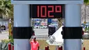 Seorang pria mengambil swafoto di samping termometer yang menunjukkan suhu 102 derajat celcius di Baker, California pada tanggal 11 Juli 2023, di tengah-tengah gelombang panas. (Photo by Frederic J. BROWN / AFP)