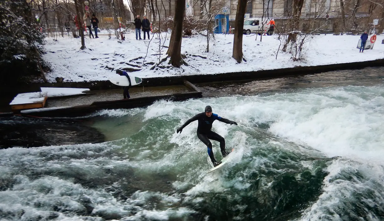Seorang pria menaklukkan ombak saat berselancar di Sungai Eisbach selama hari musim dingin di Munich, Jerman, 4 Januari 2017. Eisbach merupakan sungai buatan dengan panjang dua kilometer dan arusnya pun merupakan buatan. (Mark RALSTON/AFP)