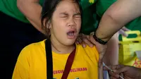Ekspresi seorang siswi saat disuntikkan vaksin anti-dengue di Sekolah Dasar Parang di Marikina, sebelah barat Manila, Senin (4/4). Filipina telah menyuntikkan vaksin pertama di dunia untuk penyakit DBD itu kepada 1 juta pelajar. (NOEL CELIS/AFP)