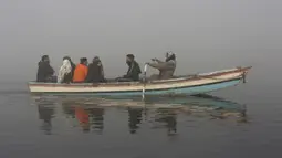 Orang-orang naik perahu di Sungai Ravi saat kabut tebal menyelimuti Lahore, Pakistan, Selasa (30/11/2021). Lahore secara konsisten menempati peringkat sebagai salah satu kota terburuk di dunia untuk polusi udara. (AP Photo/K.M. Chaudary)