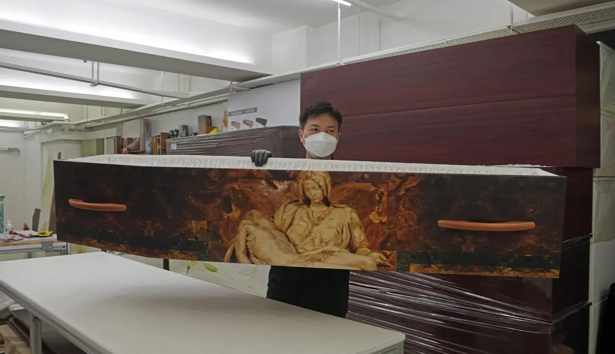 Seorang pekerja mengangkat peti mati kertas di pabrik LifeArt di Hong Kong, Jumat, 18 Maret 2022. LifeArt, sebuah perusahaan di Hong Kong sedang mencoba membuat alternatif peti mati dari kardus yang diklaim ramah lingkungan. (AP Photo/Kin Cheung)