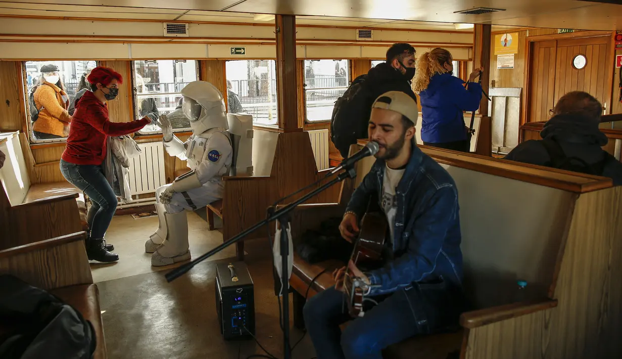 Seorang pria berpakaian astronaut melintasi Bosphorus dengan kapal feri saat kampanye untuk mempromosikan Pameran Luar Angkasa NASA di Istanbul, Turki, pada 5 Desember 2021. Pameran ini akan menampilkan modul khusus dari luar angkasa dan puluhan instrumen berteknologi tinggi. (AP Photo/Emrah Gurel)