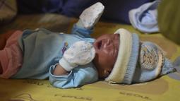 Bayi laki-laki berusia sehari, Muhammad Al Aksa, beristirahat di tempat pengungsian sementara di kota Mamuju, Sulawesi, Selasa (19/1/2021).  Basarnas menyebut hingga pukul 16.00 WIB, Senin (18/1/2021) sebanyak 84 orang meninggal akibat gempa yang terjadi di Sulawesi Barat (Sulbar). (AFP/Firdaus)