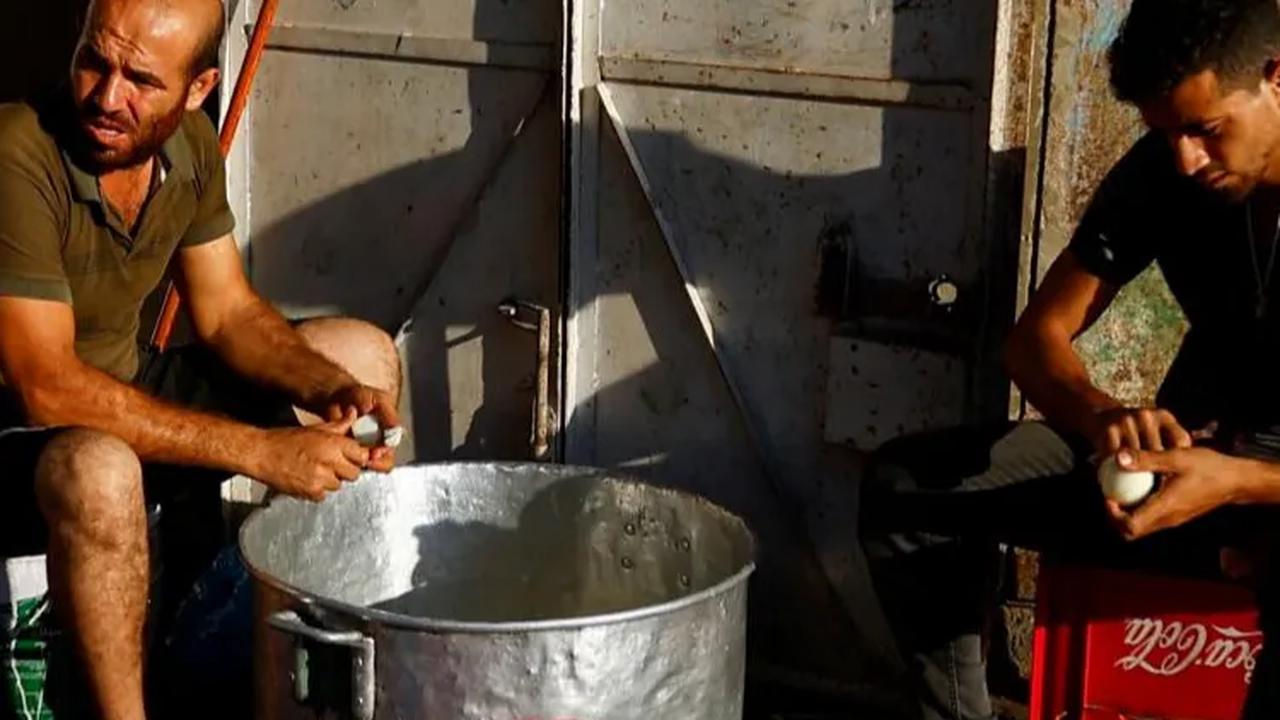 Dua pria Palestina di Khan Younis terlihat sibuk mengupas bawang saat akan diolah menjadi makanan untuk warga.