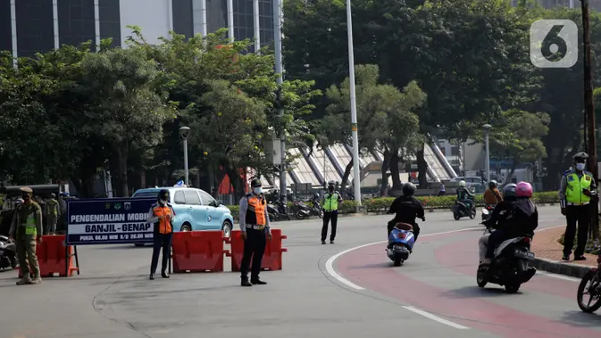 Petugas mengawasi kendaraan yang melintas di pos penyekatan ganjil-genap di Bundaran Senayan, Minggu (5/9/2021). Pembatasan kendaraan dengan sistem pelat nomor kendaraan ini tetap berlaku di akhir pekan, Sabtu dan Minggu. (/Angga Yuniar)