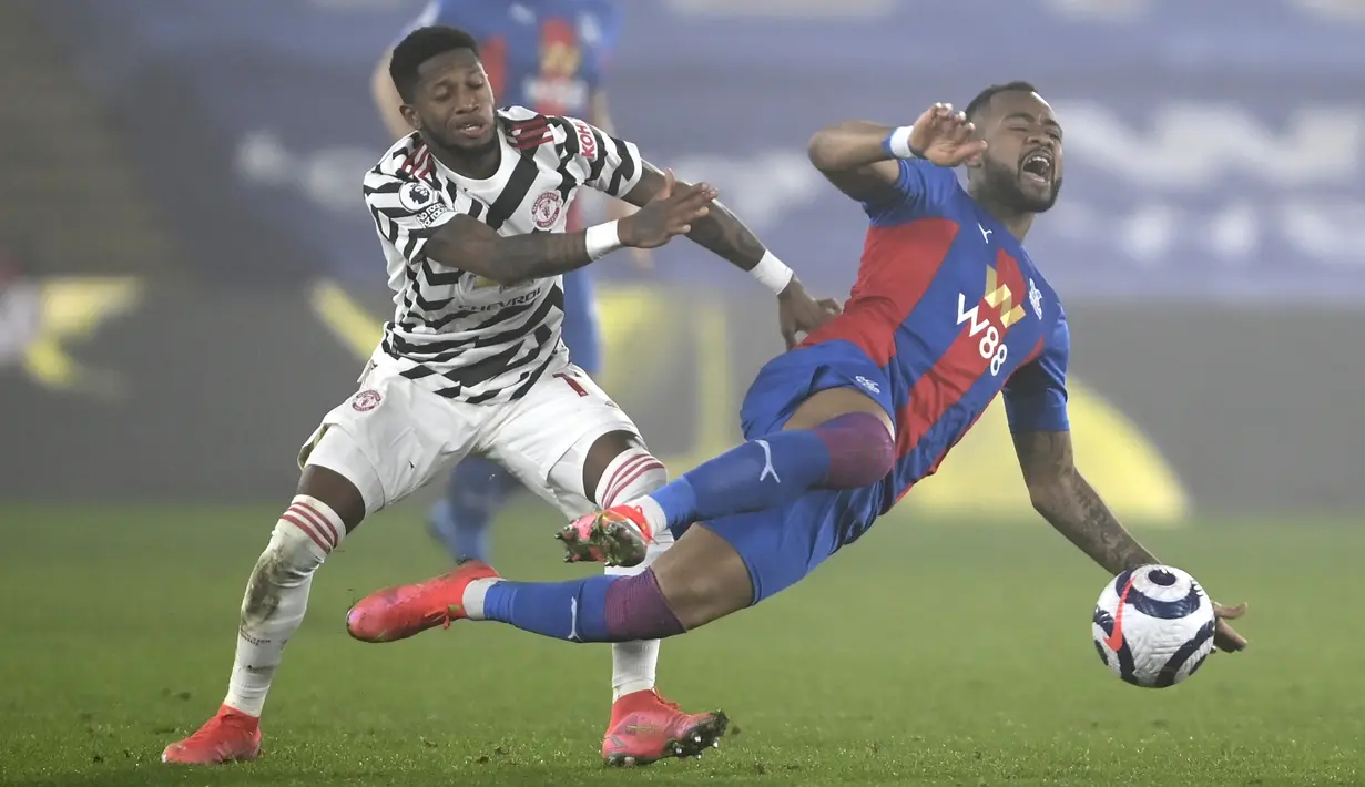 Striker Crystal Palace, Jordan Ayew (kanan) terjatuh usai perebutan bola dengan gelandang Manchester United, Fred dalam laga lanjutan Liga Inggris 2020/21 pekan ke-27 di Selhurst Park, Rabu (3/3/202). Crystal Palace bermain imbang 0-0 dengan Manchester United. (AP/Mike Hewitt/Pool)