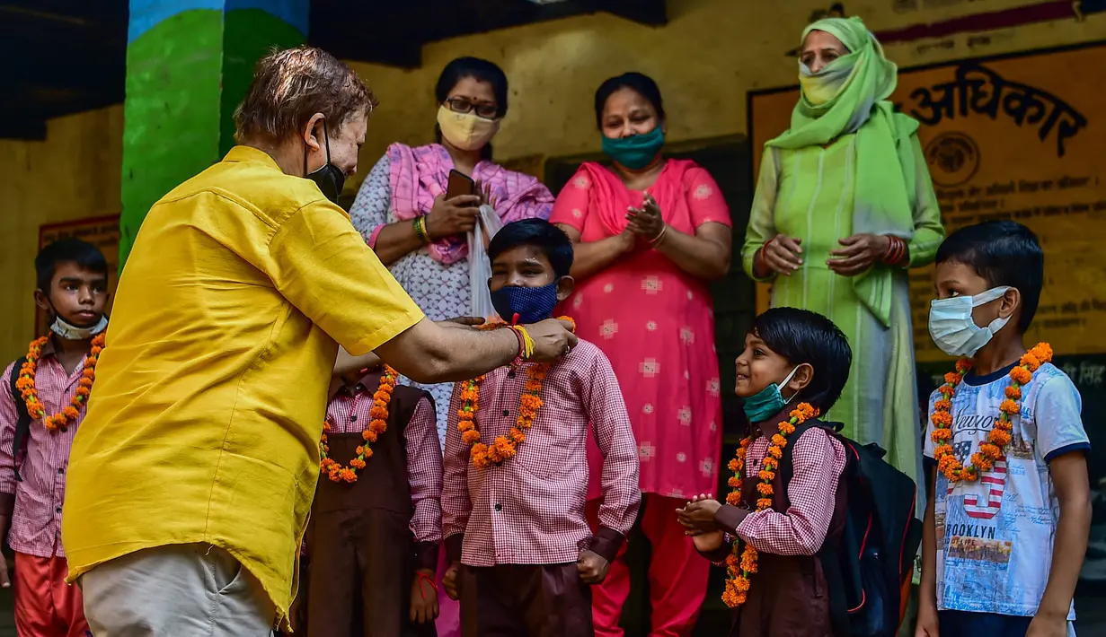 Guru menyambut siswa dengan karangan bunga di sebuah sekolah di Allahabad, India, Rabu (1/9/2021). Pemerintah negara bagian melonggarkan lockdown COVID-19 untuk lembaga pendidikan yang memungkinkan siswa menghadiri sekolah tatap muka dengan 50 persen kapasitas. (SANJAY KANOJIA/AFP)
