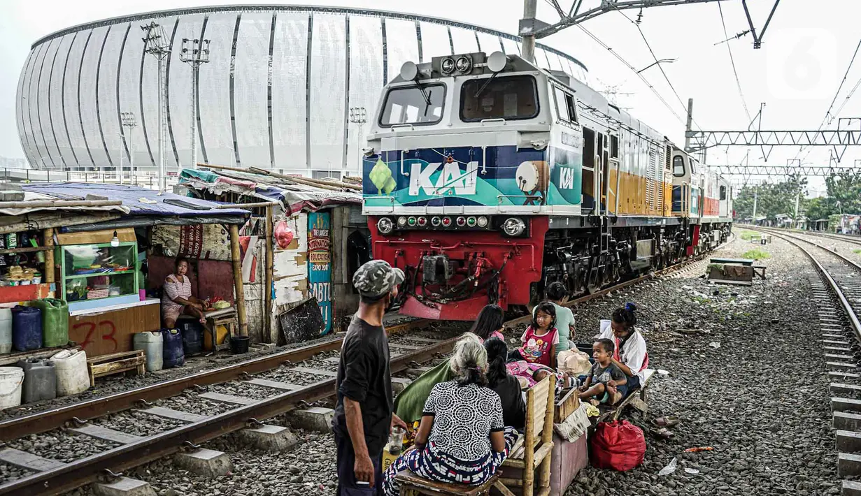 Warga berkumpul dekat lahan bekas Kampung Bayam saat kereta melintas, Jakarta, Rabu (11/5/2022). PT Jakpro memulai pembangunan rumah susus di atas lahan bekas gusuran Kampung Bayam yang disebut Kampung Susun Bayam. (Liputan6.com/Faizal Fanani)