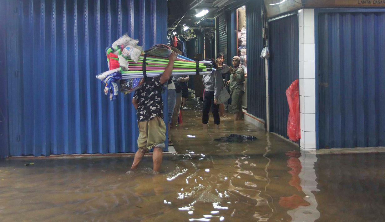 Genangan air berdampak langsung pada kegiatan jual beli. Jumlah pengunjung menurun karena akses yang sulit dan kondisi pasar yang kurang nyaman. Tampak dalam foto, aktivitas pedagang dan pembeli di Pasar Cipulir, Jakarta, Jumat (23/1/2026). (merdeka.com/Arie Basuki)