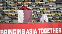 Seorang suporter membawa bendera negara saat mendukung Timnas Qatar saat laga Piala Asia 2019 di Zayed Sports City Stadium, Abu Dhabi (17/1/2019). (AFP/Khaled Desouki)