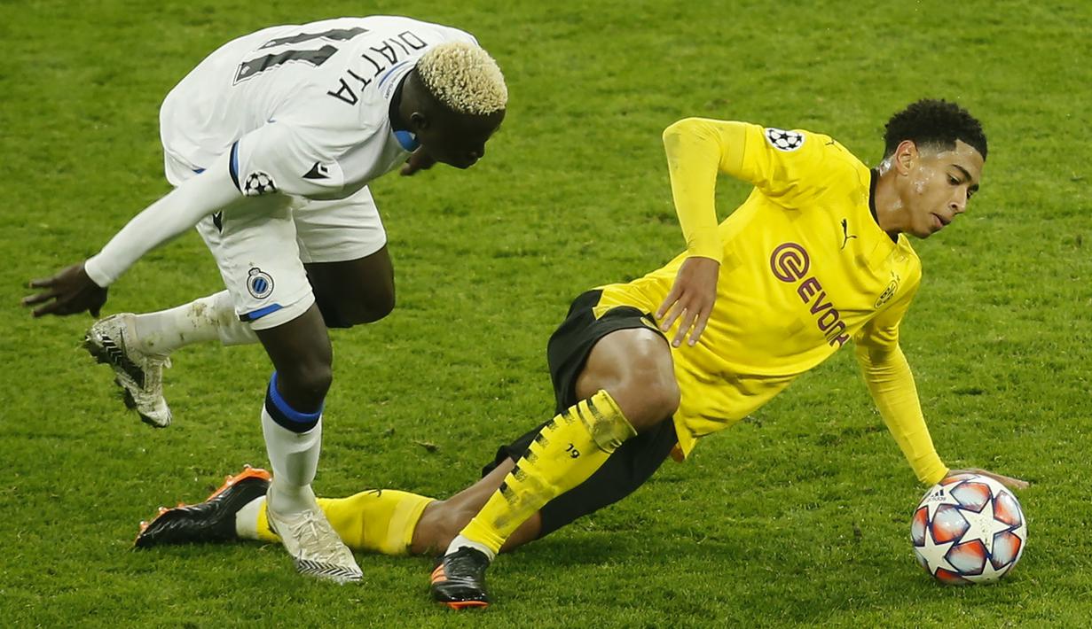 Gelandang Borussia Dortmund, Jude Bellingham, berebut bola dengan gelandang Club Brugge, Krepin Diatta, pada laga lanjutan Liga Champions di Signal Iduna Park, Rabu (25/11/2020) dini hari WIB. Borussia Dortmund menang 3-0 atas Club Brugge. (AFP/Leon Kuegeler/pool)