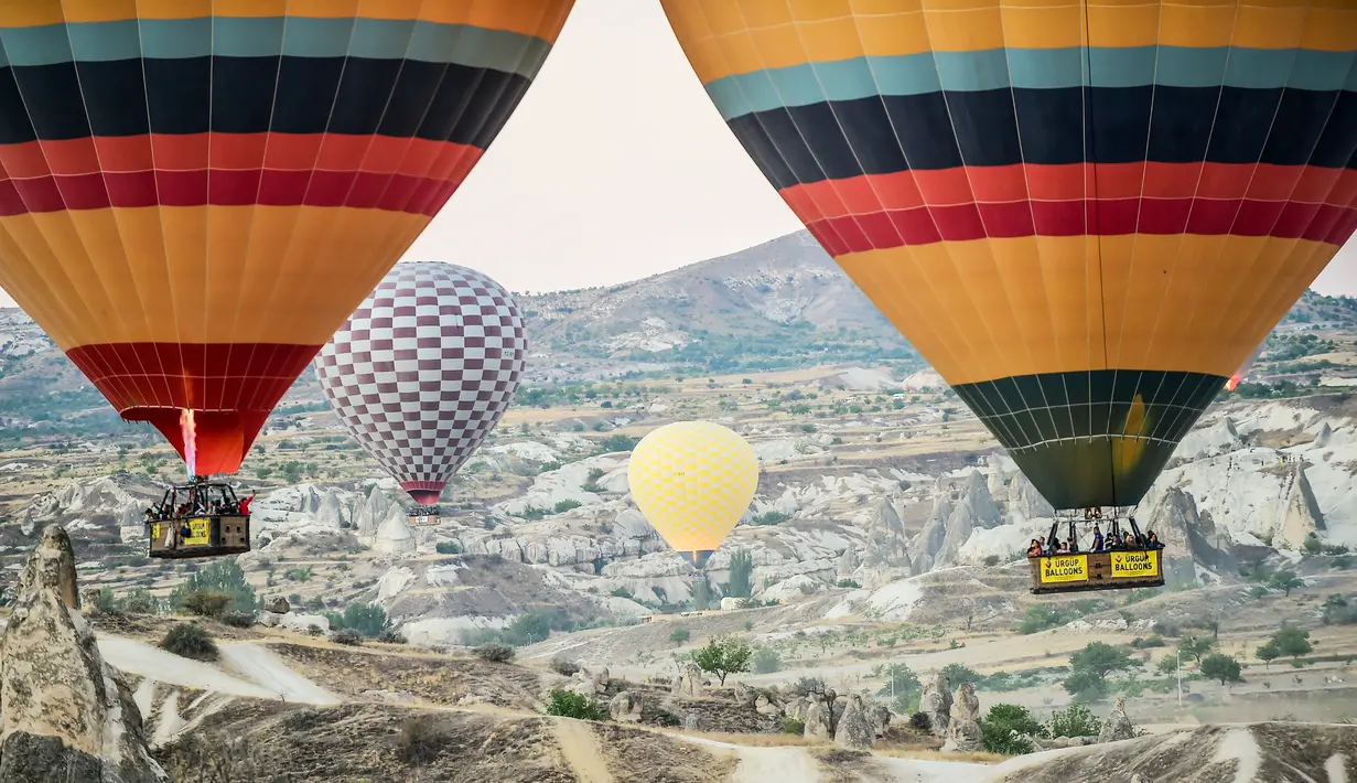 Sejumlah wisatawan terbang menaiki balon udara panas di atas Nevsehir di wilayah Cappadocia, Turki (5/9). Balon udara panas yang terbang di atas Cappadocia juga menjadi pemandangan menarik bagi para wisatawan. (AFP Photo/Yasin Akgul)