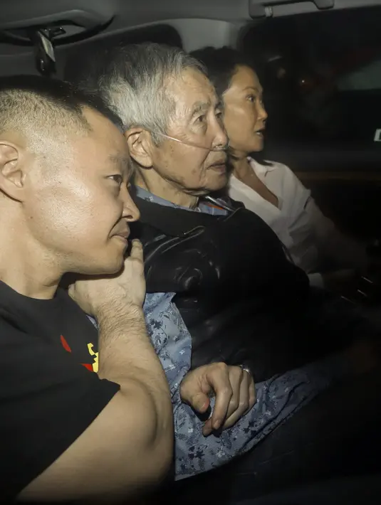 Fujimori, dengan mengenakan masker wajah dan oksigen tambahan, keluar dari pintu penjara dan masuk ke dalam sebuah mobil sport yang dikemudikan oleh menantunya. (Renato PAJUELO / AFP)