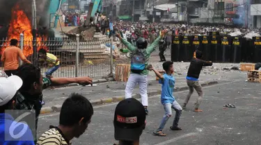 Massa menyerang Petugas kepolisian dan Satpol PP saat penggusuran Kampung Pulo, Jakarta, Kamis (20/8/2015). Penggusuran pemukiman Kampung Pulo dilakukan oleh 2.200 personel gabungan untuk normalisasi Sungai Ciliwung. (Liputan6.com/Herman Zakharia)