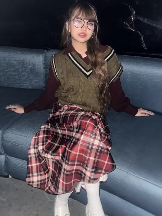 Ghea cosplay menjadi Betty La Fea dengan mengenakan knit vest coklat dipadukan inner kemeja lengan panjang dan rok tartan merah. Kacamata besar juga dikenakan sebagai ciri khas. [@gheaindrawari]