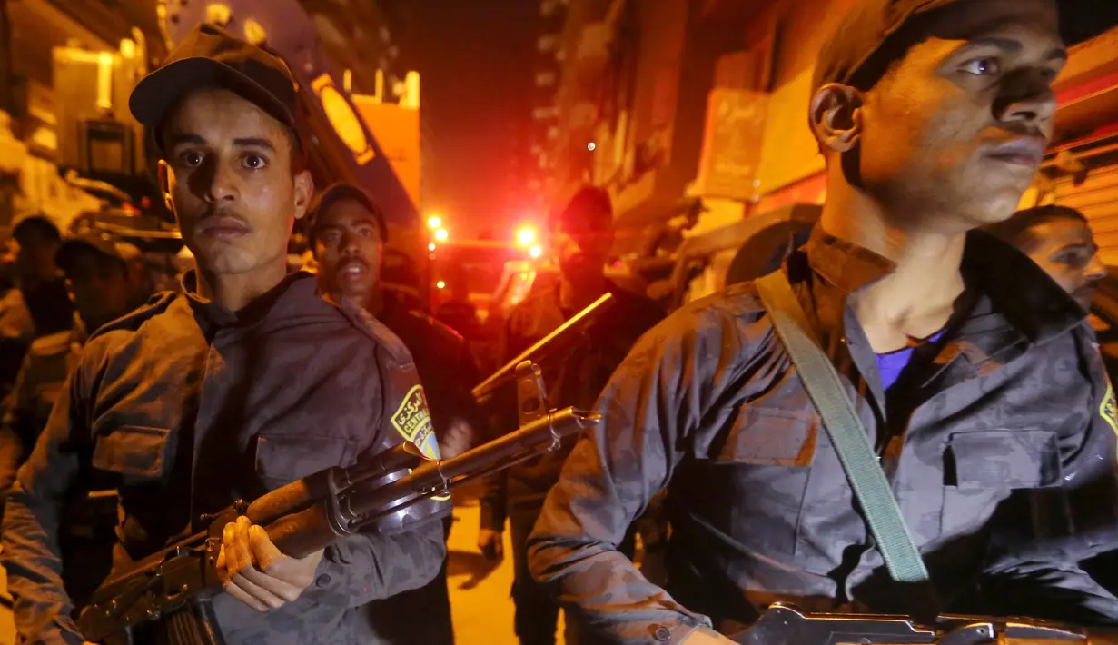 Polisi bersenjata lengkap berjaga di lokasi ledakan yang terjadi saat penggerebekan sebuah apartemen di Kairo yang diduga menjadi tempat persembunyian militan, Mesir, Kamis (21/1). Enam orang tewas, termasuk tiga polisi. (REUTERS/Mohamed Abd El Ghany)