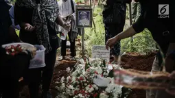 Keluarga dan kerabat menaburkan bunga di makam almarhum Amoroso Katamsi di (TPU) Tanah Wakaf Pondok Labu, Jakarta, Selasa (17/4). Amoroso meninggal pada Selasa 17 April 2018 pukul 01.40 dini hari pada usia 79 tahun. (Liputan6.com/Faizal Fanani)