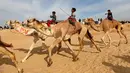 Joki cilik memacu tunggangan mereka selama Festival Balapan Unta Internasional di gurun Sarabium, Ismailia, Mesir, 12 Maret 2019. Sekitar 150 unta berkompetisi dalam delapan kategori jarak dari lima hingga 15 km.  (REUTERS/Amr Abdallah Dalsh)