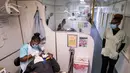 Seorang dokter gigi merawat seorang pasien ketika seorang perawat berjalan di atas kereta Phelophepa, yang diparkir di stasiun kereta Dube di Soweto, pada tanggal 17 Oktober 2023. (EMMANUEL CROSET/AFP)