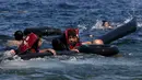 Sejumlah pengungsi Suriah menggunakan pelampung dan berenang menuju pantai setelah perahu yang ditumpangi bocor sekitar 100 m sebelum mencapai pulau Lesbon, Yunani, Minggu (13/09/2015). (REUTERS/Alkis Konstantinidis)