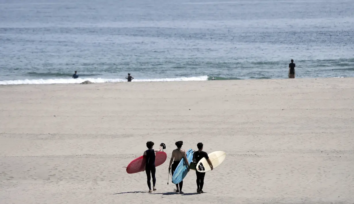 Orang-orang berjalan di pantai untuk berselancar di pantai Yotsukura, sekitar 30 kilometer (sekitar 18 mil) selatan pembangkit listrik tenaga nuklir Fukushima Daiichi, yang rusak akibat gempa bumi dan tsunami besar 11 Maret 2011, di Iwaki, timur laut Jepang, Sabtu, 26 Agustus 2023. (AP Photo/Eugene Hoshiko)