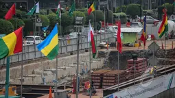 Deretan bendera negara peserta Konferensi Asia Afrika ke-60 terpasang di dinding proyek MRT kawasan Bundaran HI, Jakarta, Selasa (14/4/2015). Persiapan ini dilakukan di sepanjang jalur yang dilalui peserta negara KAA ke-60.  (Liputan6.com/Faizal Fanani)